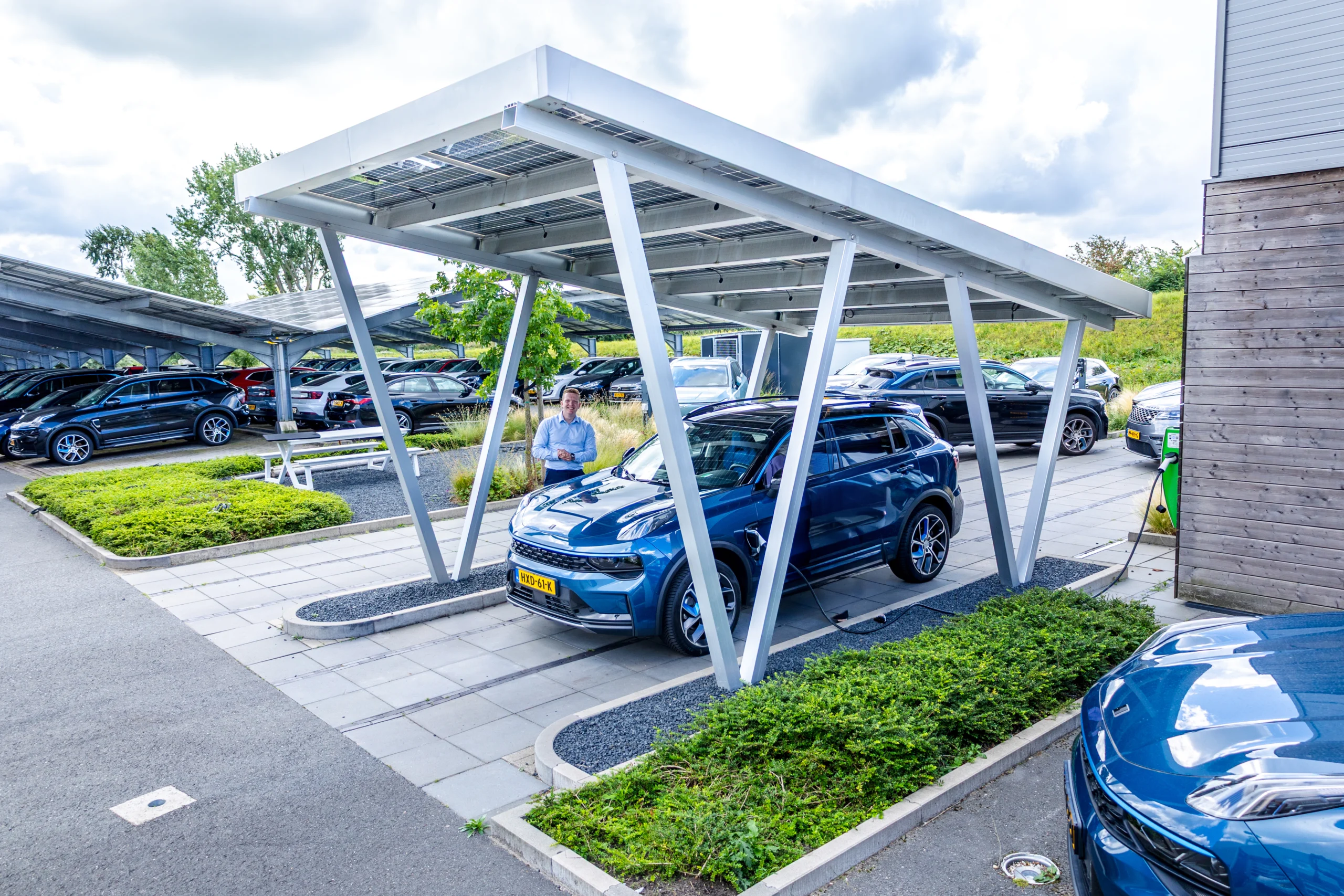 Auto’s geparkeerd onder zonnepanelen op een bedrijventerrein, combinatie van parkeren en duurzame energieopwekking voor toekomstbestendige bedrijventerreinen en werklocaties